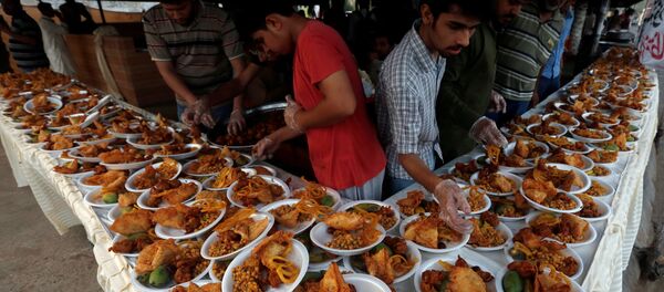 Unas personas organizan platos de comida para que los transeúntes interrumpan su ayuno durante un mes de Ramadán en Karachi - Sputnik Mundo