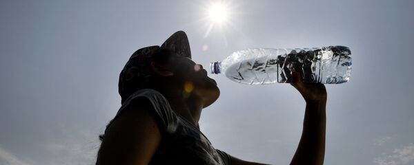 Una mujer bebe agua durante una ola de calor en Europa - Sputnik Mundo