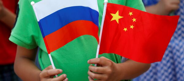 A child holds the national flags of Russia and China prior to a welcoming ceremony for Russian President Vladimir Putin outside the Great Hall of the People in Beijing, China, June 25, 2016 - Sputnik Mundo