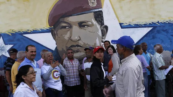 La gente venezolana ante una muralla con la imágen del expresidente de Venezuela, Hugo Chávez