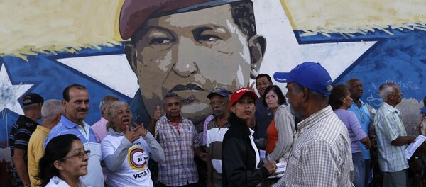 La gente venezolana ante una muralla con la imágen del expresidente de Venezuela, Hugo Chávez La gente venezolana ante una muralla con la imágen del expresidente de Venezuela, Hugo Chávez - Sputnik Mundo
