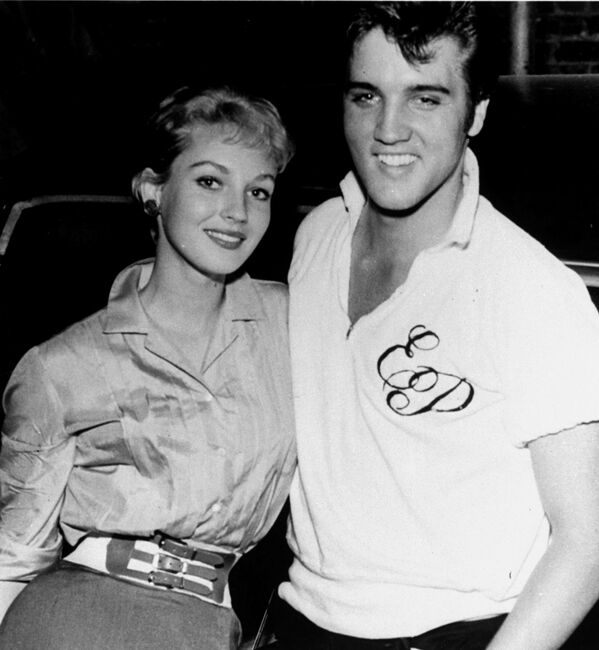 Elvis Presley, cantante de rock and roll cuando se convirtió en actor de cine, se presenta con la invitada de la casa, Venetia Stevenson, estrella de Hollywood recientemente apodada La chica más fotogénica del mundo en un concurso de revistas de fotografía. A Elvis y sus invitados vieron saliendo por la puerta trasera de un teatro del centro a principios del 9 de agosto de 1957, donde asistieron a la presentación privada de su última película, Loving You. - Sputnik Mundo