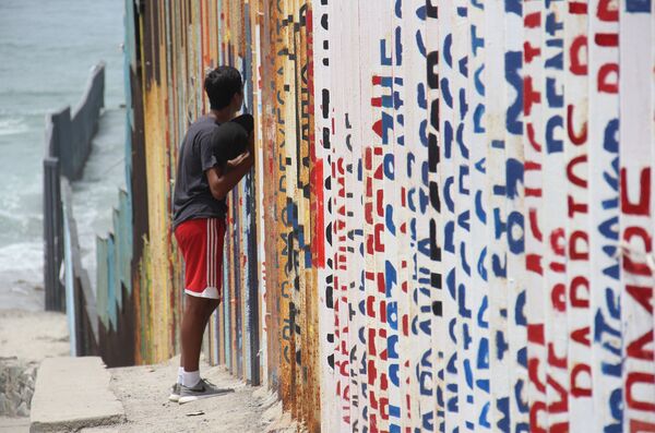 Un joven habla con sus familiares a través del muro que separa México y EEUU - Sputnik Mundo