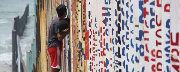 Un joven habla con sus familiares a través del muro que separa México y EEUU - Sputnik Mundo