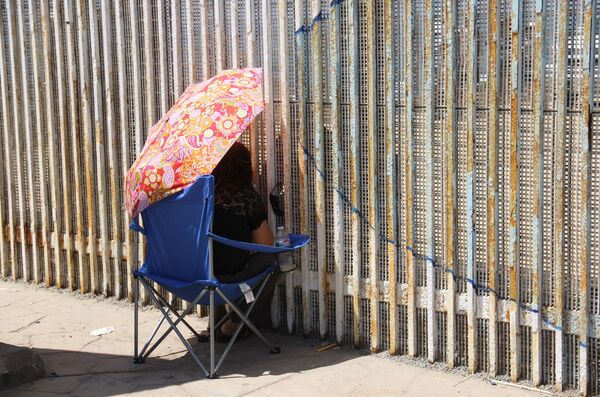 Una mujer habla con sus familiares a través del muro que separa México y EEUU - Sputnik Mundo