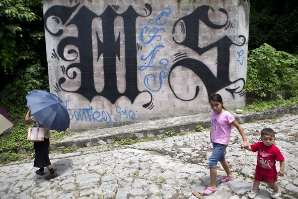 Unos niños pasean al lado de un muro pintado con los símbolos del MS-13 en El Salvador (archivo) Unos niños pasean al lado de un muro pintado con los símbolos del MS-13 en El Salvador (archivo) - Sputnik Mundo