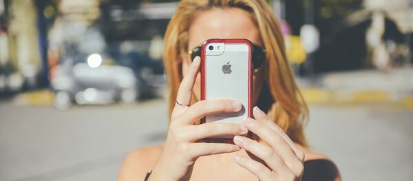 Una chica con un teléfono móvil iPhone de Apple - Sputnik Mundo