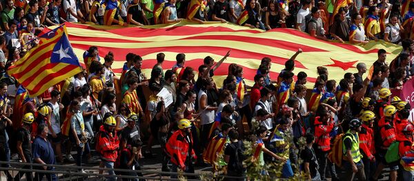Estudiantes llevan una bandera separatista catalana mientras asisten a una manifestación en favor del referéndum de independencia - Sputnik Mundo