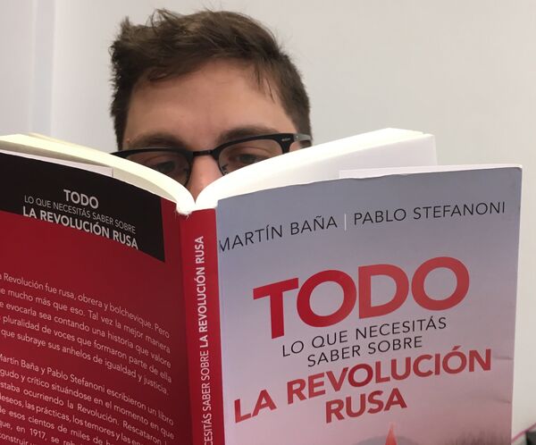 Una persona lee el libro 'Todo lo que necesitás saber sobre la Revolución Rusa' - Sputnik Mundo