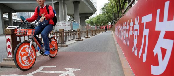 Un ciclista chino cerca del cartel que dice Que viva el gran partido Comunista de China - Sputnik Mundo