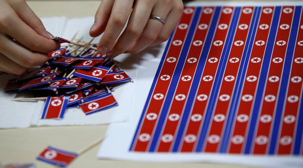 Miembro del club de fanes 'Sengun-joshi' ('Chicas militares ante todo') haciendo decoraciones con banderas de Corea del Norte. - Sputnik Mundo