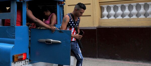 Un hombre, que lleva una camiseta de la bandera de EEUU, se baja de un vehículo en la Habana, Cuba - Sputnik Mundo