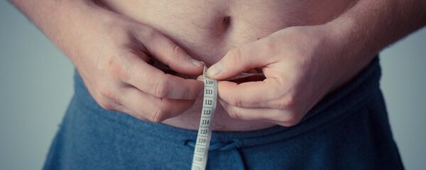 Un hombre se mide la barriga con una cinta métrica Un hombre se mide la barriga con una cinta métrica - Sputnik Mundo