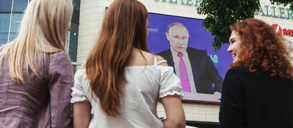 Unas jóvenes rusas están viendo un discurdo del presidente de Rusia, Vladímir Putin, por la televisión - Sputnik Mundo