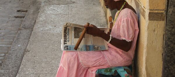 Una mujer cubana lee y fuma un puro en las calles de La Habana (imagen referencial) - Sputnik Mundo