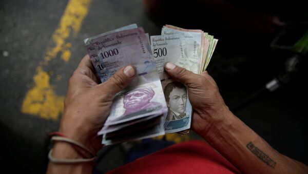 Un trabajador cuenta bolívares venezolanos en una gasolinera de la petrolera estatal venezolana PDVSA en Caracas - Sputnik Mundo