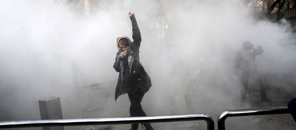 FILE - In this Saturday, Dec. 30, 2017 file photo taken by an individual not employed by the Associated Press and obtained by the AP outside Iran, a university student attends a protest inside Tehran University while a smoke grenade is thrown by anti-riot Iranian police, in Tehran, Iran - Sputnik Mundo