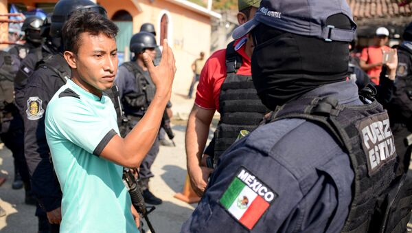 A relative argues with a police officer, near where an exchange of gunfire took place between residents and members of a local, self-appointed community police force which according to local media, left 11 dead in La Concepcion, Guerrero - Sputnik Mundo