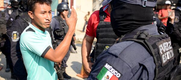 A relative argues with a police officer, near where an exchange of gunfire took place between residents and members of a local, self-appointed community police force which according to local media, left 11 dead in La Concepcion, Guerrero - Sputnik Mundo