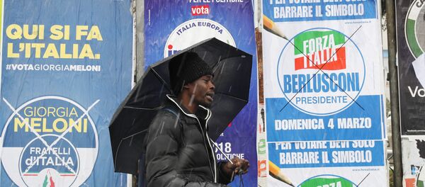 Un inmigrante africano pasa ante carteles electorales para las elecciones generales de Italia - Sputnik Mundo