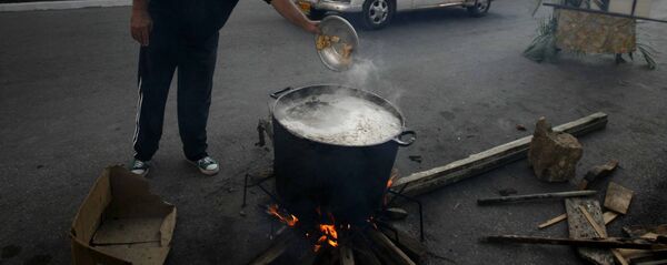 Un hombre prepara caldosa en la calle por el Aniversario de los CDR en Cuba - Sputnik Mundo