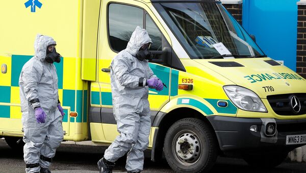 Soldados con trajes de protección caminan al lado de una ambulancia, imagen referencial - Sputnik Mundo