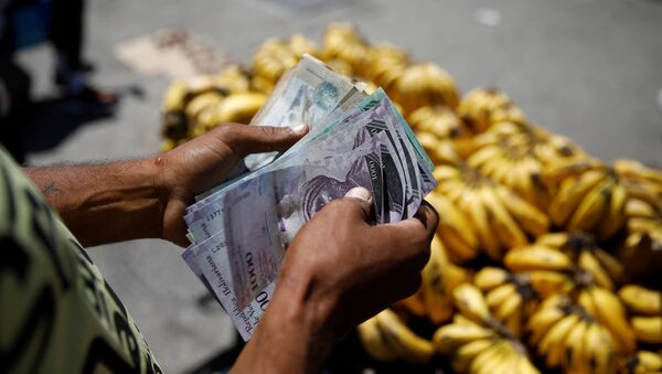 Un vendedor cuenta bolívares en Venezuela - Sputnik Mundo