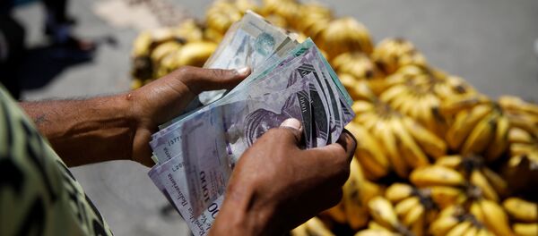 Un vendedor cuenta bolívares en Venezuela - Sputnik Mundo