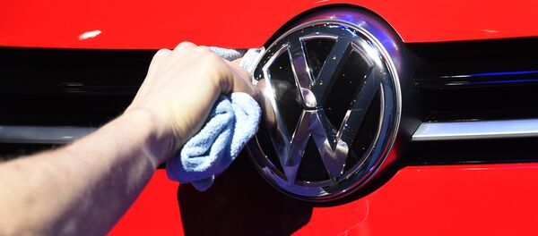 Un hombre puliendo el logotipo del automóvil del fabricante de automóviles alemán Volkswagen - Sputnik Mundo