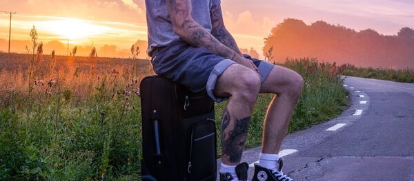 Un turista sentado sobre su equipaje  - Sputnik Mundo