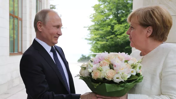 El presidente ruso Vladímir Putin regala flores a la canciller alemana, Angela Merkel
