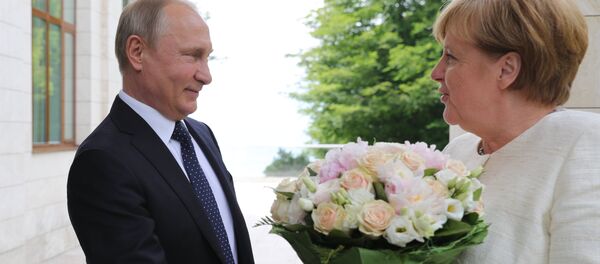El presidente ruso Vladímir Putin regala flores a la canciller alemana, Angela Merkel - Sputnik Mundo