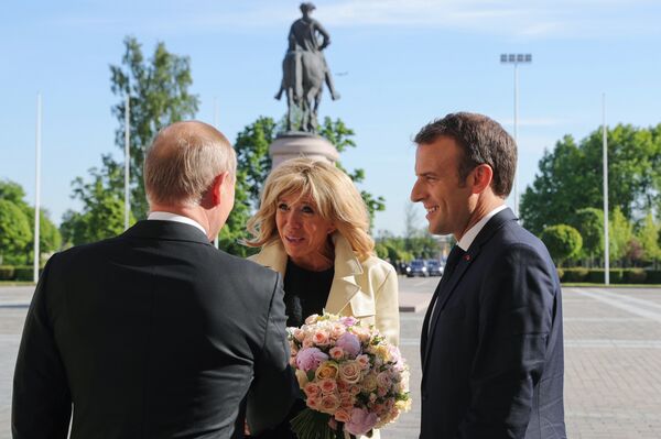 Vladímir Putin, presidente de Rusia, regalando un ramo de flores a Brigitte Macron, primera dama de Francia, durante su visita a San Petersburgo - Sputnik Mundo