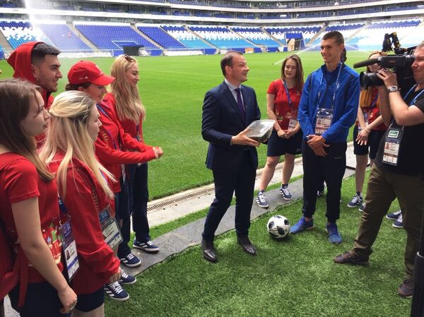 El presidente del Instituto Bering Bellingshausen para las Américas, Sergey Brilev, entrega a la joven promesa del fútbol ruso Nikita Kotin el pasto del Estadio Centenario de Montevideo para el Cosmos Arena de Samara. - Sputnik Mundo