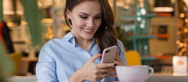 Una chica mira en la pantalla de su móvil - Sputnik Mundo