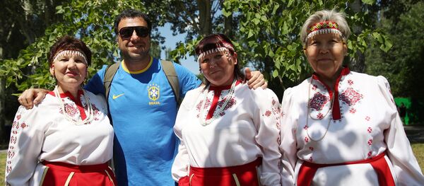 Un hincha brasileño se toma una foto con mujeres vestidas con atuendos típicos en la fiesta de Sabantuy, en Samara. - Sputnik Mundo
