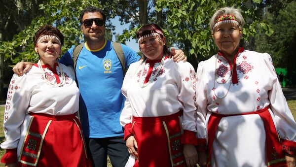 Un hincha brasileño se toma una foto con mujeres vestidas con atuendos típicos en la fiesta de Sabantuy, en Samara. - Sputnik Mundo