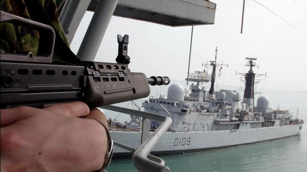 A UK Marine stands guard aboard the Royal Fleet Auxiliary forward repair ship Diligence ducked near to UK Royal Navy's destroyer Cardiff D108 - Sputnik Mundo