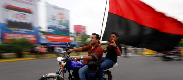 Dos motociclistas con una bandera del Frente Sandinista de Liberación Nacional de Nicaragua. Dos motociclistas con una bandera del Frente Sandinista de Liberación Nacional de Nicaragua. - Sputnik Mundo