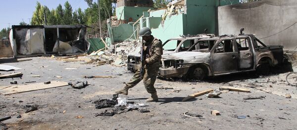 Un miembro de las fuerzas de seguridad afganas junto a vehículos dañados después de una explosión, Afganistán - Sputnik Mundo