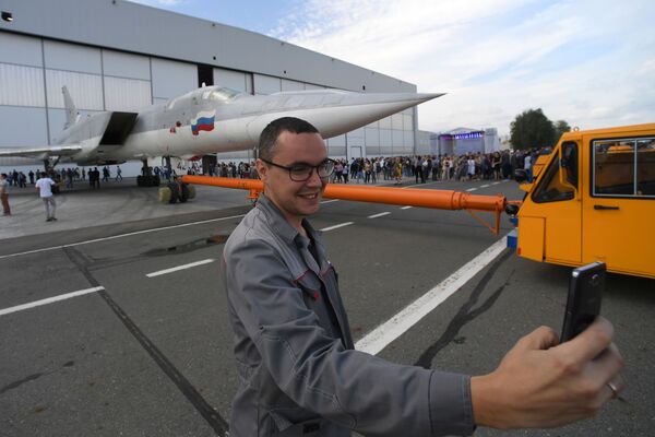 Un empleado de la fábrica se hace una selfi con con la aeronave de fondo durante la implementación de las pruebas terrestres y de vuelo del bombardero modernizado Tu-22M3M en la fábrica de aviones Gorbunov de Kazán - Sputnik Mundo