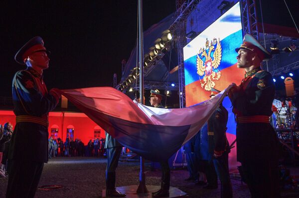 Las fiestas siguieron por la noche. En la foto, unos soldados rusos sostienen la bandera en San Petersburgo. - Sputnik Mundo