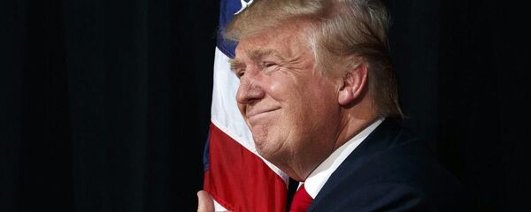 El presidente Donald Trump abraza la bandera de EEUU (archivo) El presidente Donald Trump abraza la bandera de EEUU (archivo) - Sputnik Mundo