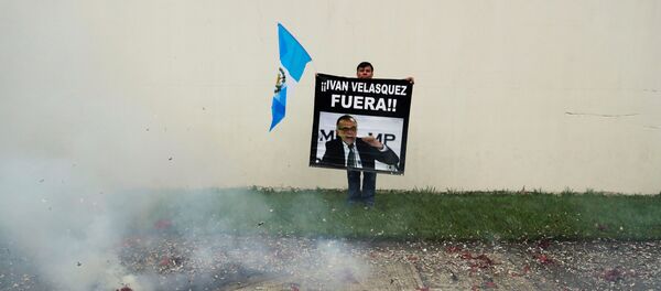 Un manifestante sostiene un cartel frente a la sede de la CICIG en Guatemala - Sputnik Mundo
