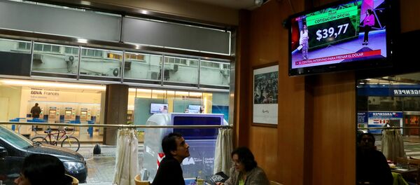 Un hombre ve por la TV las tasas de cambio del dólar en Buenos Aires, Argentina (archivo) Un hombre ve por la TV las tasas de cambio del dólar en Buenos Aires, Argentina (archivo) - Sputnik Mundo