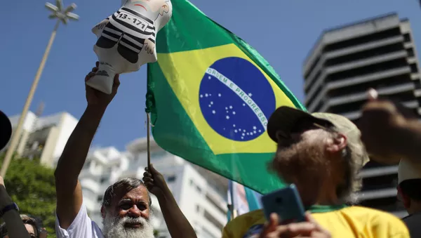 Un manifestante con la bandera de Brasil - Sputnik Mundo