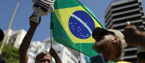Un manifestante con la bandera de Brasil - Sputnik Mundo