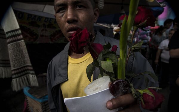 Hombre muestra los regalos recibidos por los demás fieles que reparten flores, dulces e imágenes - Sputnik Mundo