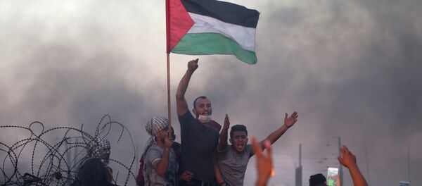 Unos jóvenes con la bandera palestina en las protestas en la frontera con Israel - Sputnik Mundo
