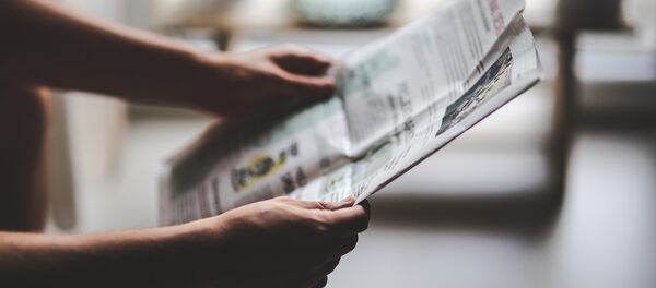 Una persona con un periódico en las manos Una persona con un periódico en las manos - Sputnik Mundo